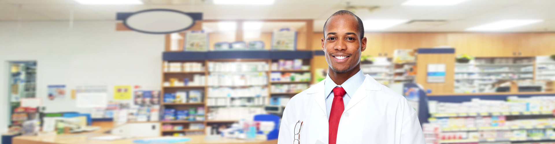 male pharmacist inside pharmacy standing and smiling