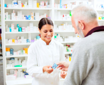 pharmacist holding capsules and customer wants to get it and they're both smiling